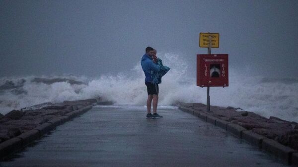 Local resident John Smith holds his 18-month-old son Owen as he stands near breaking waves on a pier ahead of the arrival of Tropical Storm Nicholas in Galveston, Texas, U.S., September 13, 2021. - Sputnik International
