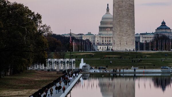 The U.S. Capitol Building is seen past the Washington Monument as people walk around the Reflecting Pool on the National Mall as the sun sets on November 28, 2021 in Washington, DC. President Biden returned to Washington after spending the Thanksgiving Holiday with family in Nantucket and immediately met with members of his medical team to discuss the newly discovered Omicron variant of the coronavirus. - Sputnik International