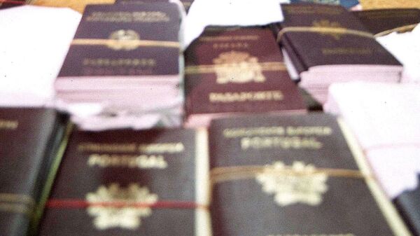 German Heinz Paul Bruggemann, 61, (C) and French Jean-Claude Villechenoux, 46, (L-covering his face) sit next to fake European passports and visa seals at the immigration police bureau in Bangkok, late 16 February 2004.  Villechenoux and Bruggemann have been arrested by Thai immigration police officers for attempting to smuggle out of the country more then 400 fake European passports and visa seals, police said.  AFP PHOTO  (Photo by AFP) - Sputnik International