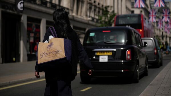 A woman carrying a reusable shopping bag crosses the Regent Street shopping district, in London, Wednesday, May 18, 2022 - Sputnik International