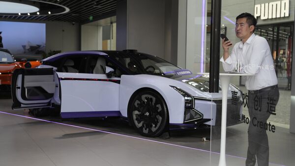 A man talks on his phone near an electric car from Chinese automaker HiPhi at a showroom in Beijing, Thursday, April 13, 2023. Global and Chinese automakers plan to unveil more than a dozen new electric SUVs, sedans and muscle cars this week at the Shanghai auto show, their first full-scale sales event in four years in a market that has become a workshop for developing electrics, self-driving cars and other technology. - Sputnik International