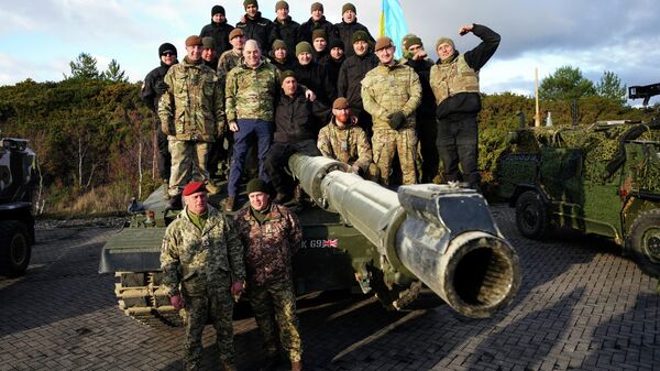 Britain's Defense Secretary Ben Wallace, centre left, poses with Ukrainian soldiers during a visit at Bovington Camp, a British Army military base where they are training on Challenger 2 tanks, in Dorset, England, February 2023.  - Sputnik International