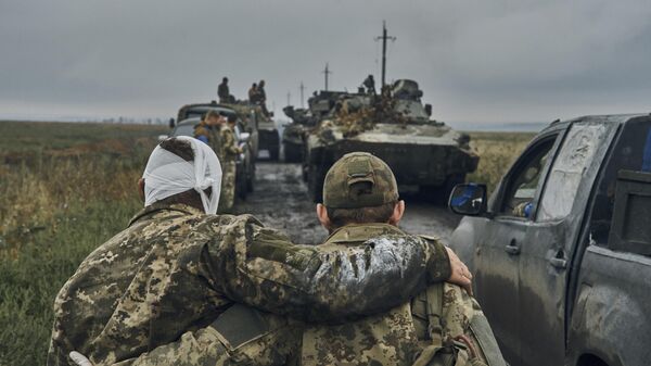 A Ukrainian soldier helps a wounded comrade in the Kharkov region, Ukraine, on Sept. 12, 2022.  - Sputnik International