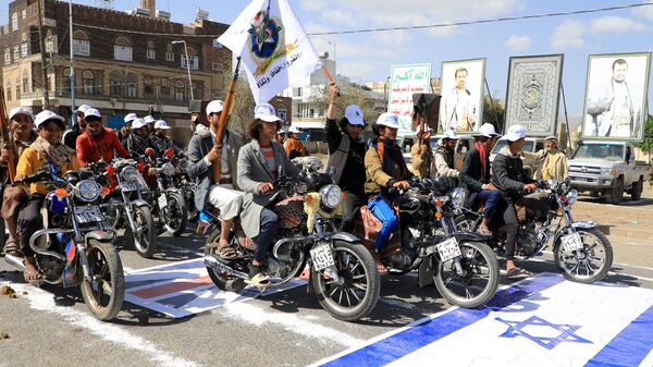 Yemeni men riding motorcycles drive over an Israeli flag painted on the asphalt in the Houthi-run capital Sanaa, during a march in support of the Palestinians amid ongoing battles between Israel and Hamas militants in the Gaza Strip, on February 29, 2024.  - Sputnik International