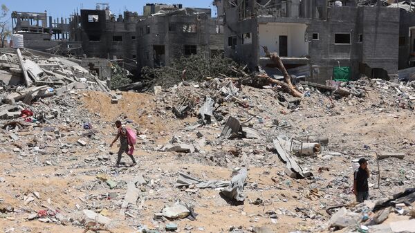 Palestinians walks next to destroyed buildings in the Jabalia refugee camp in the northern Gaza on June 1, 2024.  - Sputnik International
