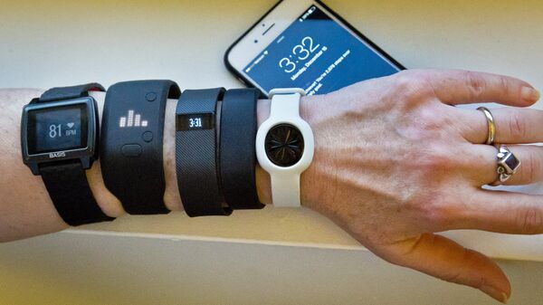 Fitness trackers, from left, Basis Peak, Adidas Fit Smart, Fitbit Charge, Sony SmartBand, and Jawbone Move, are posed for a photo next to an iPhone, in New York (File) - Sputnik International