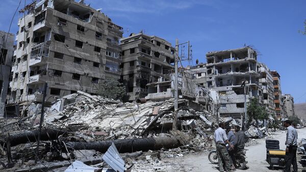 People stand in front of damaged buildings, in the town of Douma, the site of a suspected chemical weapons attack, near Damascus, Syria, Monday, April 16, 2018 - Sputnik International