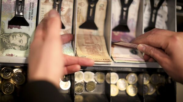 A man holds a 100 peso bill in the cashier of a restaurant in Buenos Aires, Argentina, Wednesday, Aug. 14, 2019. President Mauricio Macri announced economic relief for poor and working-class Argentines that include an increased minimum wage, reduced payroll taxes, a bonus for informal workers and a freeze in gasoline prices. The conservative leader said Wednesday he's acting in recognition of the anger Argentines expressed in Sunday's primary election, when Macri trailed his populist rival by 15 percentage points. - Sputnik International