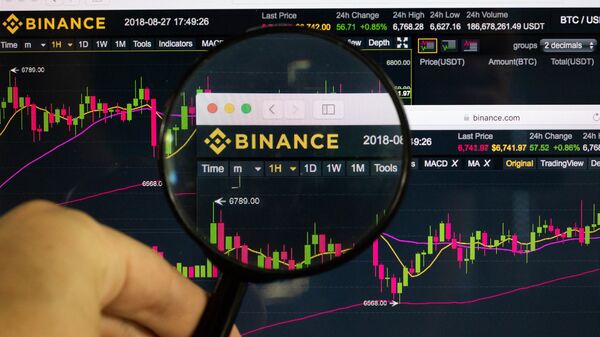 Man holding magnifying glass over Binance logo - Sputnik International